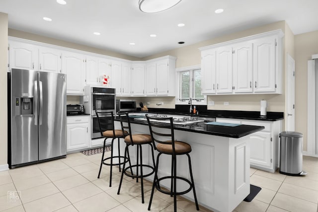 401 Jason Ln, Schaumburg, IL 60173 - kitchen with appliances with stainless steel finishes, dark countertops, white cabinets, a kitchen island, and a kitchen bar