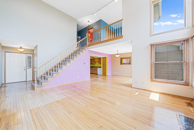 9963 Constitution Dr, Orland Park, IL 60462 - unfurnished living room featuring stairway, hardwood / wood-style floors, rail lighting, and a high ceiling