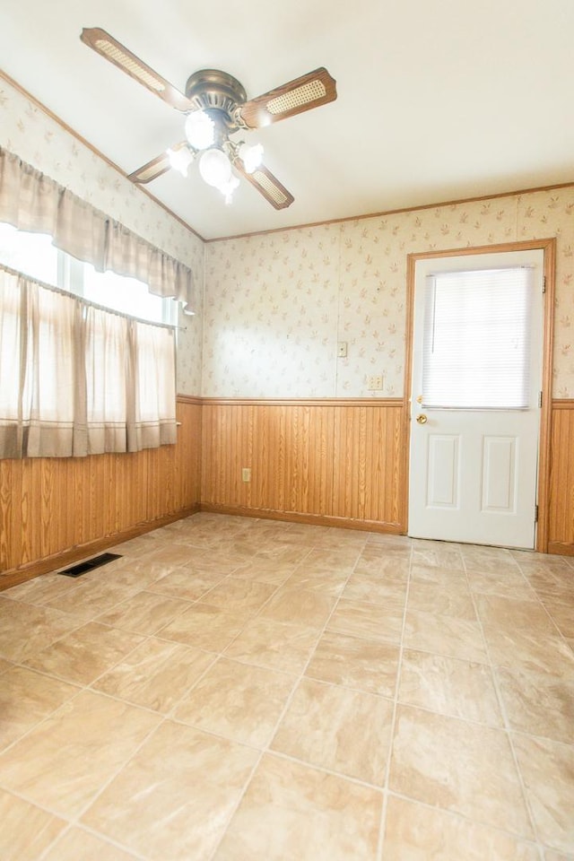 1602 N Jefferson Ave, Dixon, IL 61021 - empty room featuring a wainscoted wall, a ceiling fan, wooden walls, and wallpapered walls