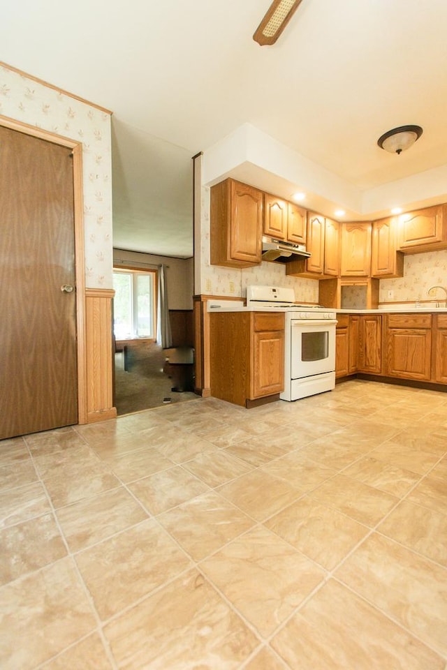 1602 N Jefferson Ave, Dixon, IL 61021 - kitchen featuring white range, under cabinet range hood, wallpapered walls, light countertops, and wainscoting