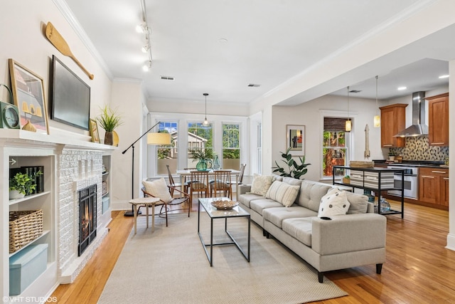 5359 N Paulina St Unit 2, Chicago, IL 60640 - living area featuring a brick fireplace, light wood-type flooring, track lighting, and ornamental molding