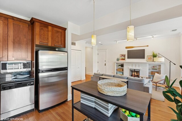 5359 N Paulina St Unit 2, Chicago, IL 60640 - kitchen featuring stainless steel appliances, light wood-type flooring, brown cabinets, a fireplace, and decorative light fixtures