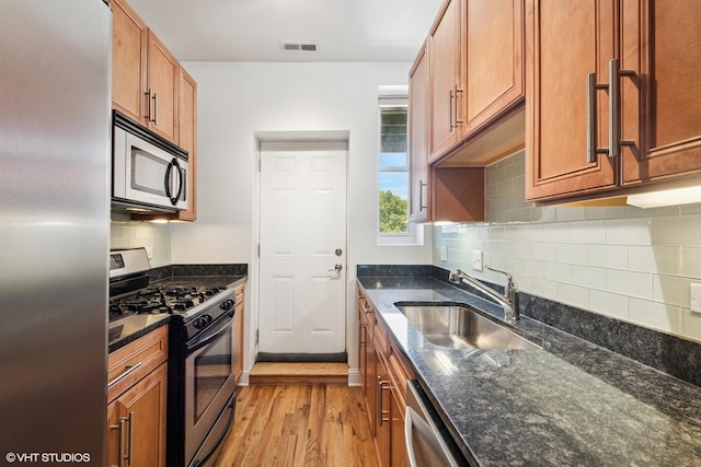 3414 N Racine Ave Unit 2, Chicago, IL 60657 - kitchen with stainless steel appliances, light wood-style floors, backsplash, dark stone counters, and brown cabinets