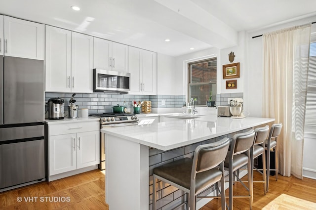 1585 Ridge Ave Unit 110, Evanston, IL 60201 - kitchen with stainless steel appliances, a breakfast bar, white cabinets, decorative backsplash, and recessed lighting
