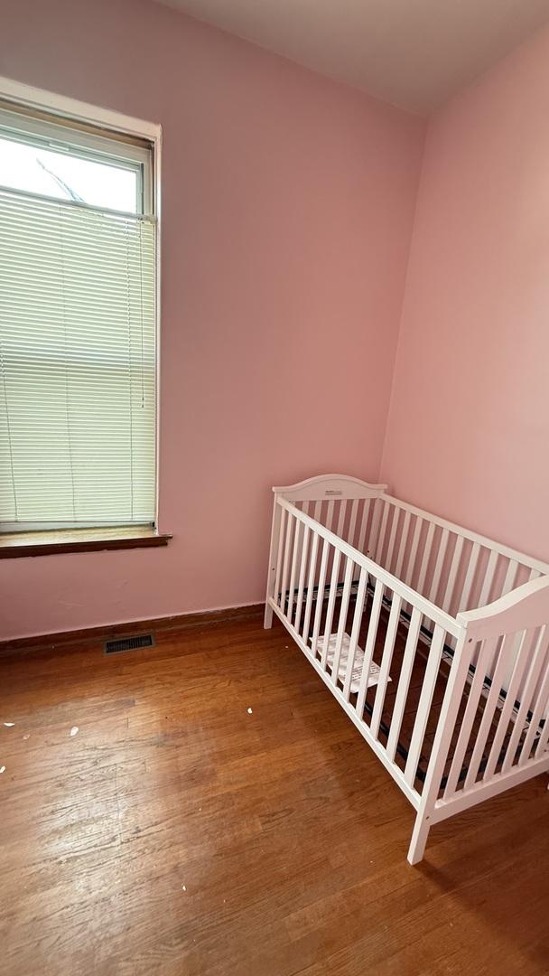 2816 S Lowe St, Chicago, IL 60616 - unfurnished bedroom with wood finished floors, baseboards, and a crib