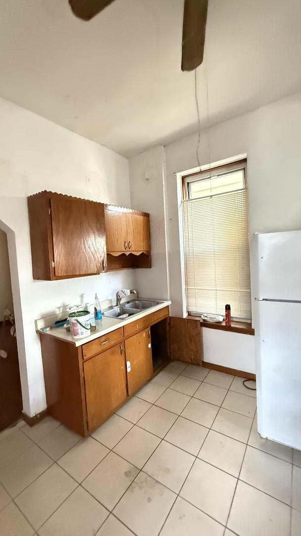 2816 S Lowe St, Chicago, IL 60616 - kitchen featuring freestanding refrigerator, a sink, light countertops, brown cabinets, and light tile patterned floors