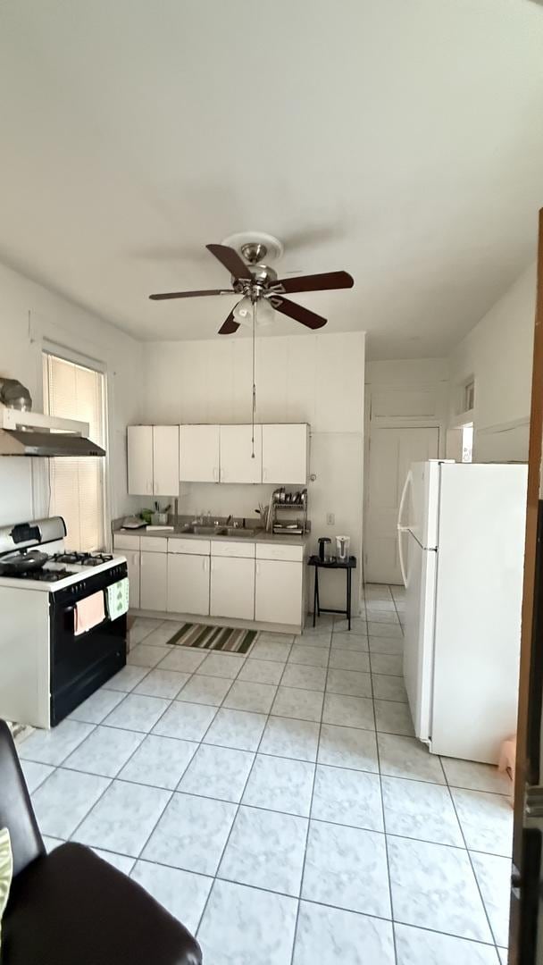 2816 S Lowe St, Chicago, IL 60616 - kitchen featuring gas stove, freestanding refrigerator, under cabinet range hood, white cabinetry, and light tile patterned floors