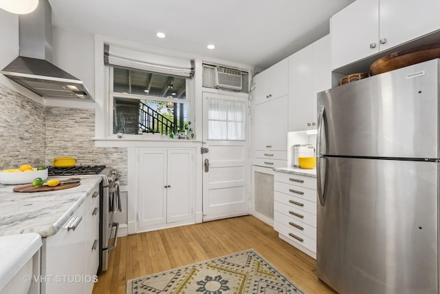 542 Michigan Ave Unit 1, Evanston, IL 60202 - kitchen featuring stainless steel appliances, wall chimney range hood, light wood-type flooring, backsplash, and white cabinetry