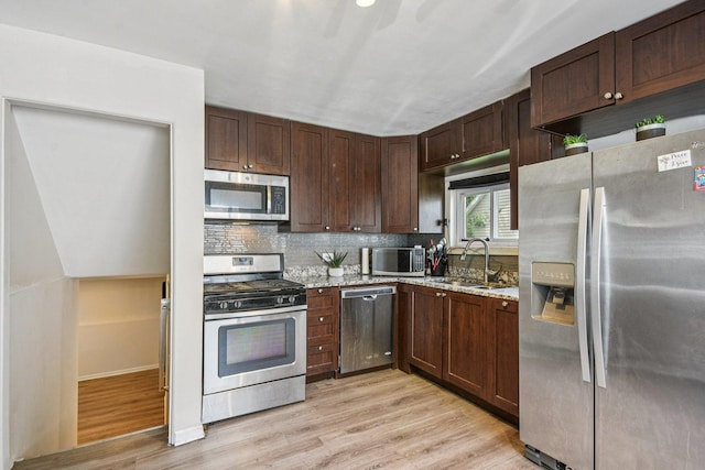17852 Walter St, Lansing, IL 60438 - kitchen featuring appliances with stainless steel finishes, light wood-style flooring, tasteful backsplash, light stone countertops, and dark brown cabinets