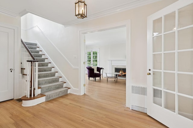 720 Ingleside Pl, Evanston, IL 60201 - entryway featuring ornamental molding, light wood-type flooring, stairs, a lit fireplace, and radiator heating unit