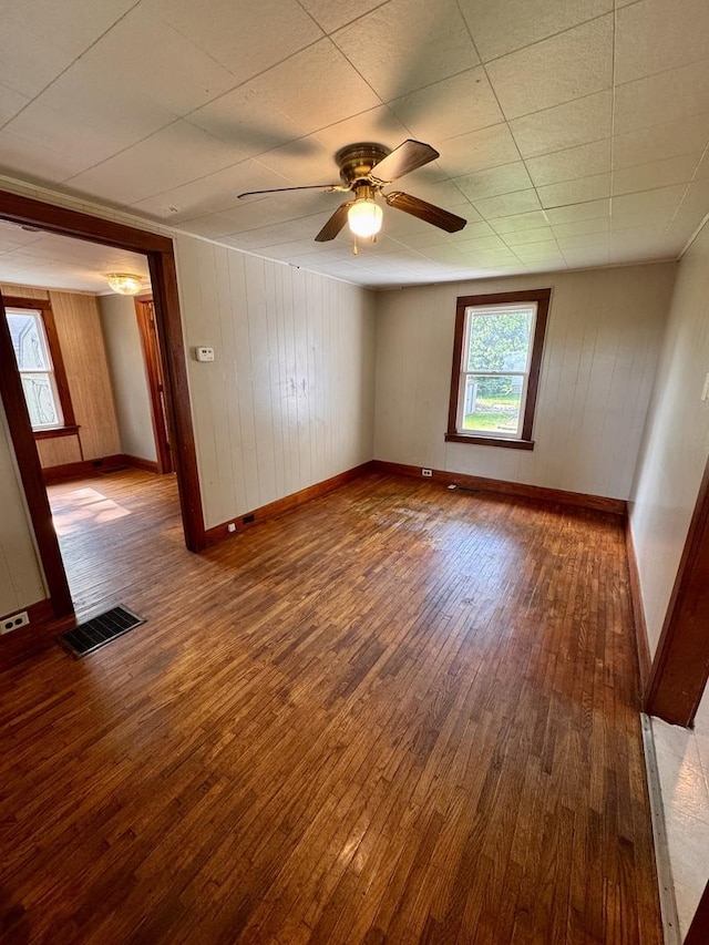 1202 E Water St, Pontiac, IL 61764 - spare room with wood-type flooring, a ceiling fan, baseboards, and wooden walls
