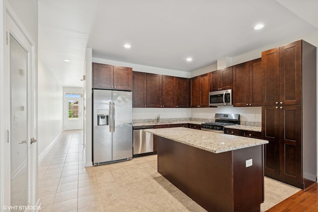 763 Verandah Dr, Hanover Park, IL 60133 - kitchen featuring stainless steel appliances, a sink, a center island, dark brown cabinets, and light stone countertops