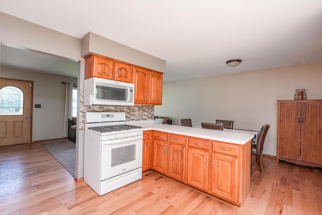 350 Kathy Dr, Bourbonnais, IL 60914 - kitchen with white appliances, a peninsula, light wood-style flooring, and light countertops