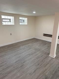 below grade area with dark wood-style flooring, baseboards, a baseboard heating unit, and recessed lighting