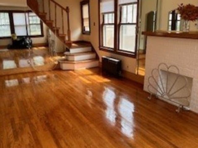unfurnished living room featuring wood finished floors, stairway, and baseboards