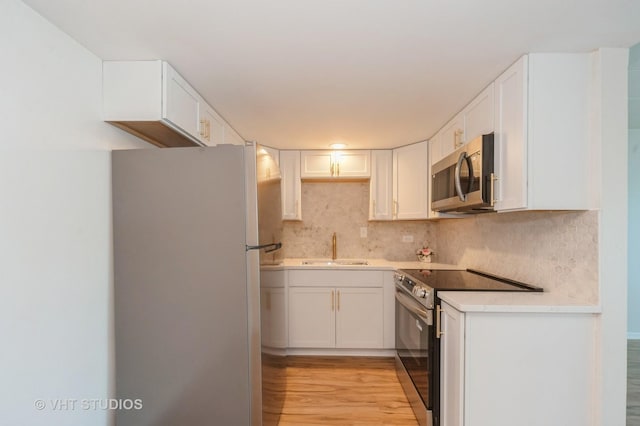 127 N Wolf Rd Unit 52A, Wheeling, IL 60090 - kitchen featuring stainless steel appliances, decorative backsplash, white cabinets, and light wood-style floors
