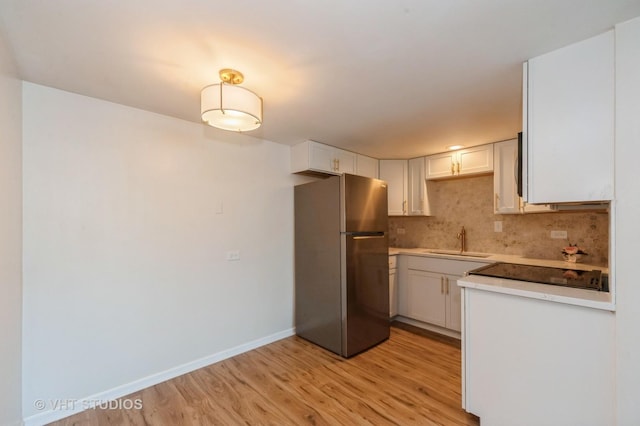 127 N Wolf Rd Unit 52A, Wheeling, IL 60090 - kitchen featuring freestanding refrigerator, light wood-type flooring, backsplash, white cabinets, and light countertops