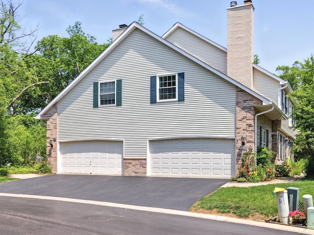1386 Laurel Oaks Dr, Streamwood, IL 60107 - view of home's exterior with a chimney, driveway, a garage, and brick siding