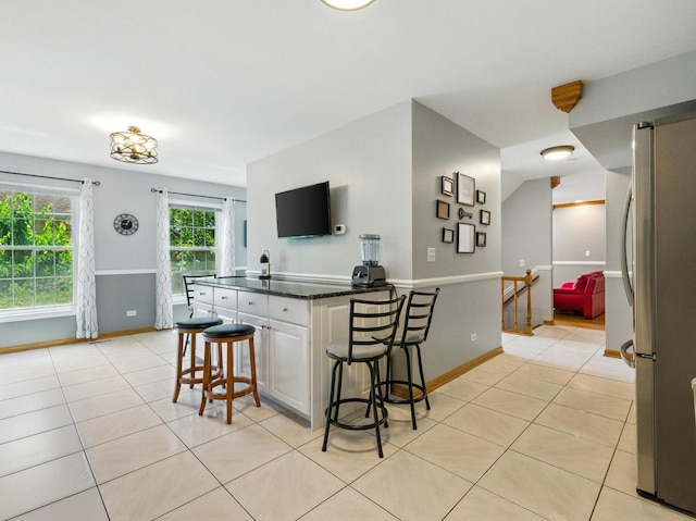 1386 Laurel Oaks Dr, Streamwood, IL 60107 - kitchen with freestanding refrigerator, a kitchen bar, light tile patterned floors, a peninsula, and white cabinetry