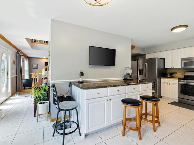 1386 Laurel Oaks Dr, Streamwood, IL 60107 - kitchen with appliances with stainless steel finishes, a breakfast bar area, white cabinets, and dark stone counters