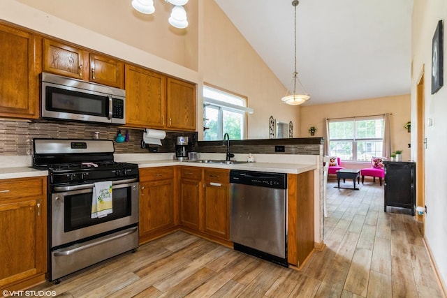 4321 Dillon St, Plano, IL 60545 - kitchen featuring appliances with stainless steel finishes, a peninsula, brown cabinetry, backsplash, and light wood-type flooring