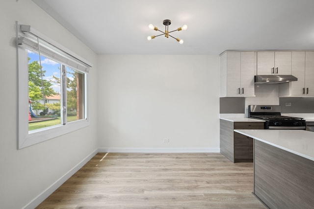 2000 Bayside Dr Unit 204, Palatine, IL 60074 - kitchen featuring stainless steel gas stove, under cabinet range hood, light countertops, a chandelier, and light wood-style floors