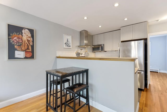 1107 Washington Blvd Unit 2E, Oak Park, IL 60302 - kitchen featuring stainless steel appliances, wall chimney range hood, light wood-type flooring, a breakfast bar, and recessed lighting