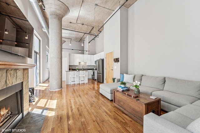 758 N Larrabee St Unit 427, Chicago, IL 60654 - living room featuring a towering ceiling, light wood finished floors, a tiled fireplace, and decorative columns