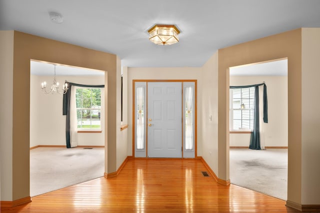 213 Stillwater Ct, Oswego, IL 60543 - entryway with light wood finished floors, a chandelier, and light colored carpet