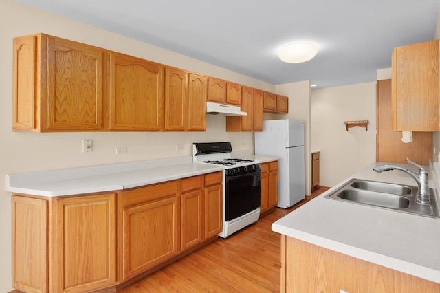 213 Stillwater Ct, Oswego, IL 60543 - kitchen featuring range with gas cooktop, freestanding refrigerator, under cabinet range hood, light wood-style floors, and light countertops