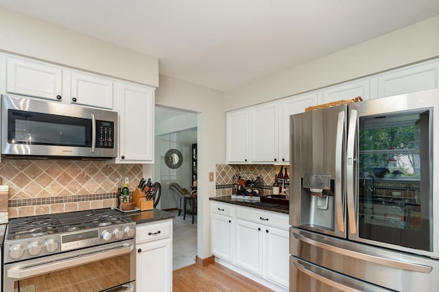 407 Anthony Ct, Oswego, IL 60543 - kitchen with stainless steel appliances, light wood-type flooring, white cabinets, backsplash, and dark stone countertops