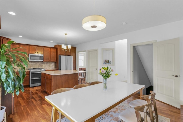 2107 Max Run Dr E, Champaign, IL 61822 - kitchen with stainless steel appliances, a center island, dark wood-style floors, tasteful backsplash, and a kitchen breakfast bar