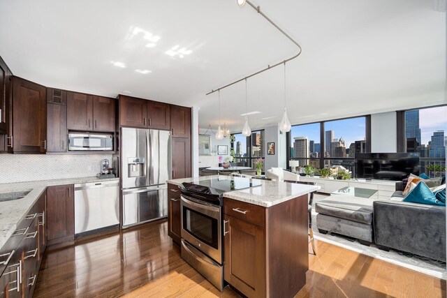 1030 N State St Unit 44L, Chicago, IL 60610 - kitchen featuring appliances with stainless steel finishes, open floor plan, wood finished floors, and tasteful backsplash