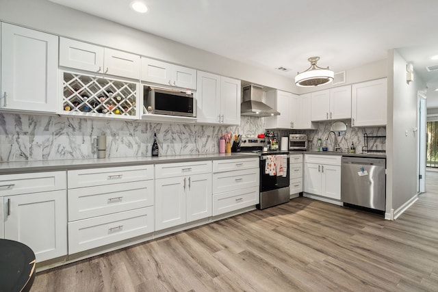 534 W Eugenie St, Chicago, IL 60614 - kitchen featuring appliances with stainless steel finishes, wall chimney range hood, white cabinetry, light wood-type flooring, and recessed lighting