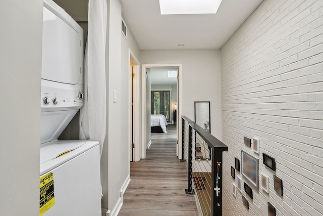 534 W Eugenie St, Chicago, IL 60614 - laundry area with stacked washer / drying machine, light wood finished floors, a skylight, and brick wall