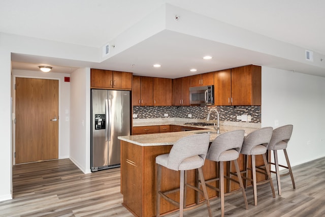 9715 Woods Dr Unit 700, Skokie, IL 60077 - kitchen featuring stainless steel appliances, a peninsula, brown cabinetry, light wood-style flooring, and recessed lighting