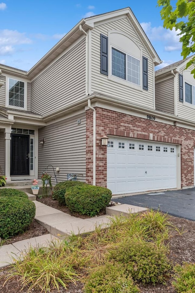 9809 Williams Dr Unit 9809, Huntley, IL 60142 - view of home's exterior with a garage, brick siding, and asphalt driveway
