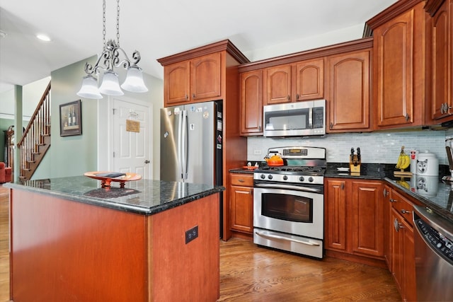 12820 Tipperary Ln, Plainfield, IL 60585 - kitchen with appliances with stainless steel finishes, wood finished floors, decorative backsplash, dark stone countertops, and a kitchen island