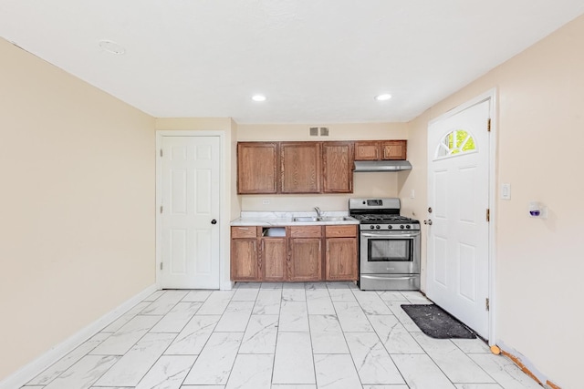 9626 S Oglesby Ave, Chicago, IL 60617 - kitchen with stainless steel gas range, light marble finish flooring, brown cabinetry, under cabinet range hood, and light countertops