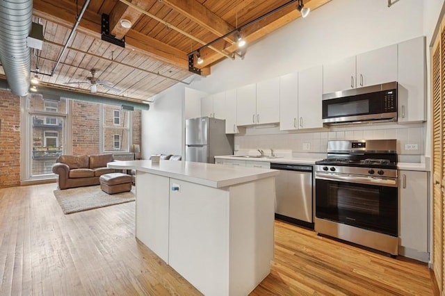 420 S Clinton St Unit 614A, Chicago, IL 60607 - kitchen featuring appliances with stainless steel finishes, wooden ceiling with exposed beams, light countertops, brick wall, and light wood-style flooring