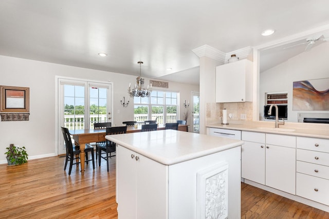 5284 Harvey Rd, Caledonia, IL 61011 - kitchen featuring a chandelier, a center island, light countertops, light wood finished floors, and white cabinets