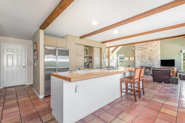 5284 Harvey Rd, Caledonia, IL 61011 - kitchen featuring stainless steel built in refrigerator, cream cabinetry, beamed ceiling, light countertops, and a stone fireplace