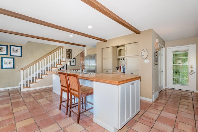 5284 Harvey Rd, Caledonia, IL 61011 - kitchen with beamed ceiling, a kitchen bar, stainless steel refrigerator, light tile patterned floors, and recessed lighting