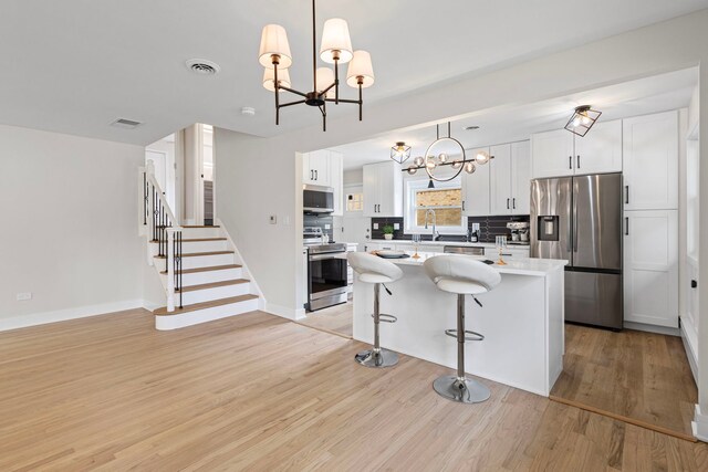 1308 Frances Pkwy, Park Ridge, IL 60068 - kitchen featuring appliances with stainless steel finishes, a chandelier, light wood-style floors, light countertops, and white cabinets
