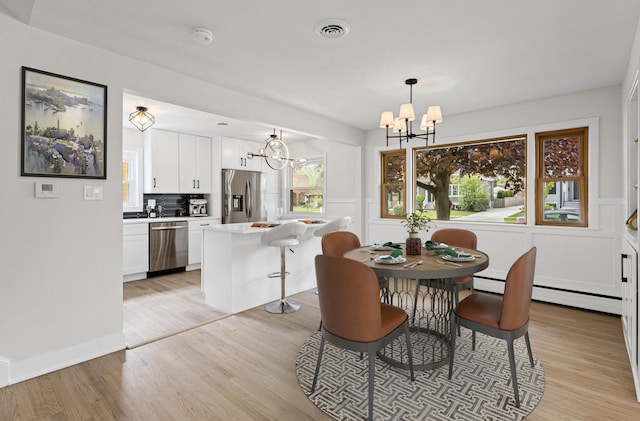 1308 Frances Pkwy, Park Ridge, IL 60068 - dining area featuring a chandelier, light wood-style floors, baseboard heating, and wainscoting