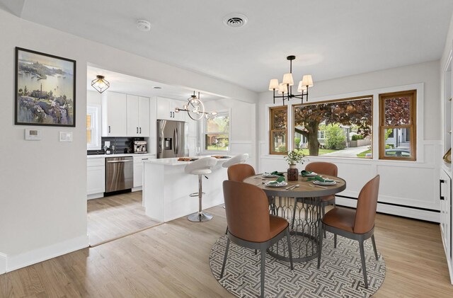 1308 Frances Pkwy, Park Ridge, IL 60068 - dining space featuring a chandelier, light wood finished floors, a wainscoted wall, and a baseboard heating unit