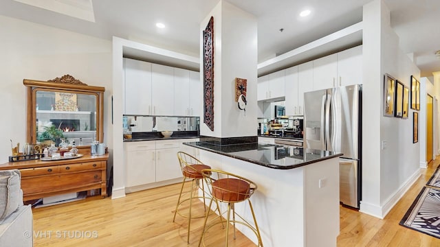 212 W Washington St Unit 1108, Chicago, IL 60606 - kitchen featuring stainless steel appliances, light wood finished floors, a center island, a breakfast bar, and white cabinets