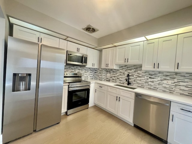 4125 N Keystone Ave Unit 605, Chicago, IL 60641 - kitchen featuring appliances with stainless steel finishes, tasteful backsplash, light countertops, light wood-style floors, and white cabinetry