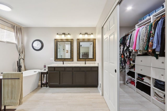 2025 Westbury Ln, Aurora, IL 60502 - bathroom with double vanity, a freestanding tub, wood finished floors, and a walk in closet