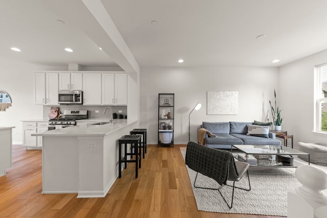 29W711 Cambridge St, Warrenville, IL 60555 - kitchen featuring stainless steel appliances, white cabinetry, a kitchen bar, a peninsula, and recessed lighting